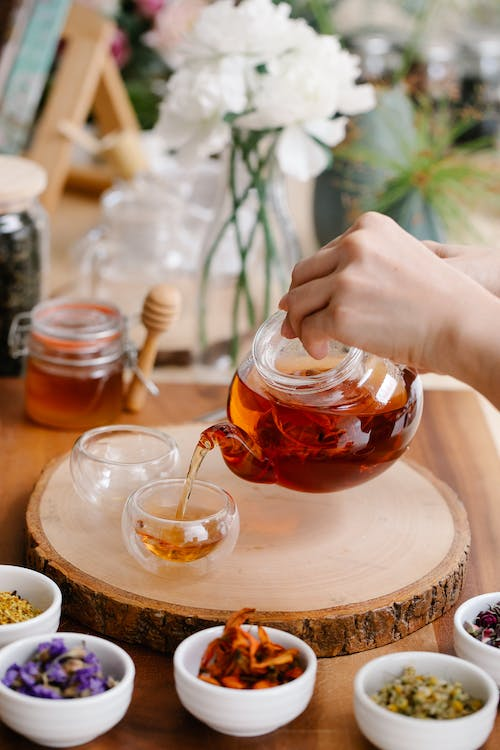 A person pouring herbal tea into a cup.