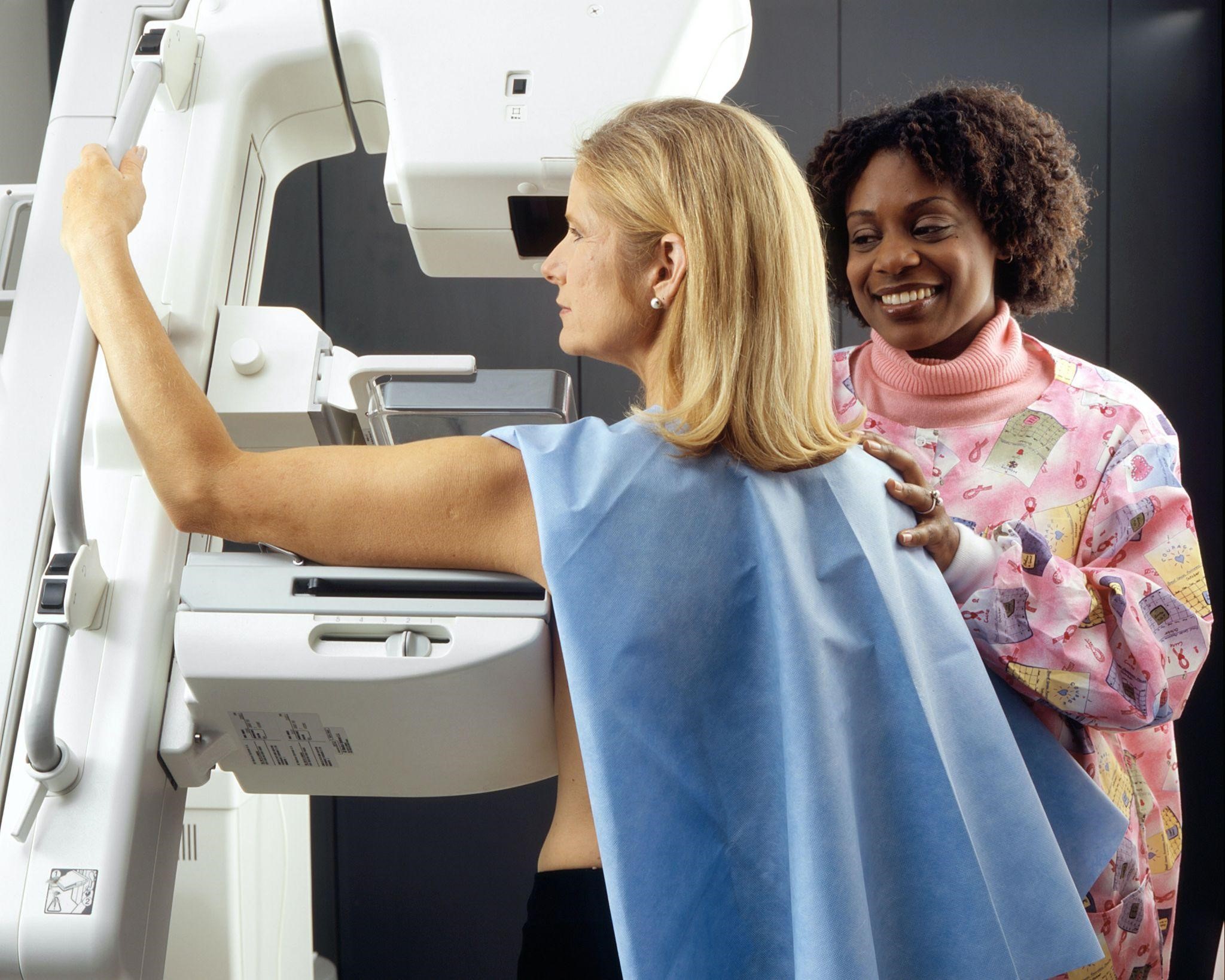 a nurse positioning a woman at a machine 