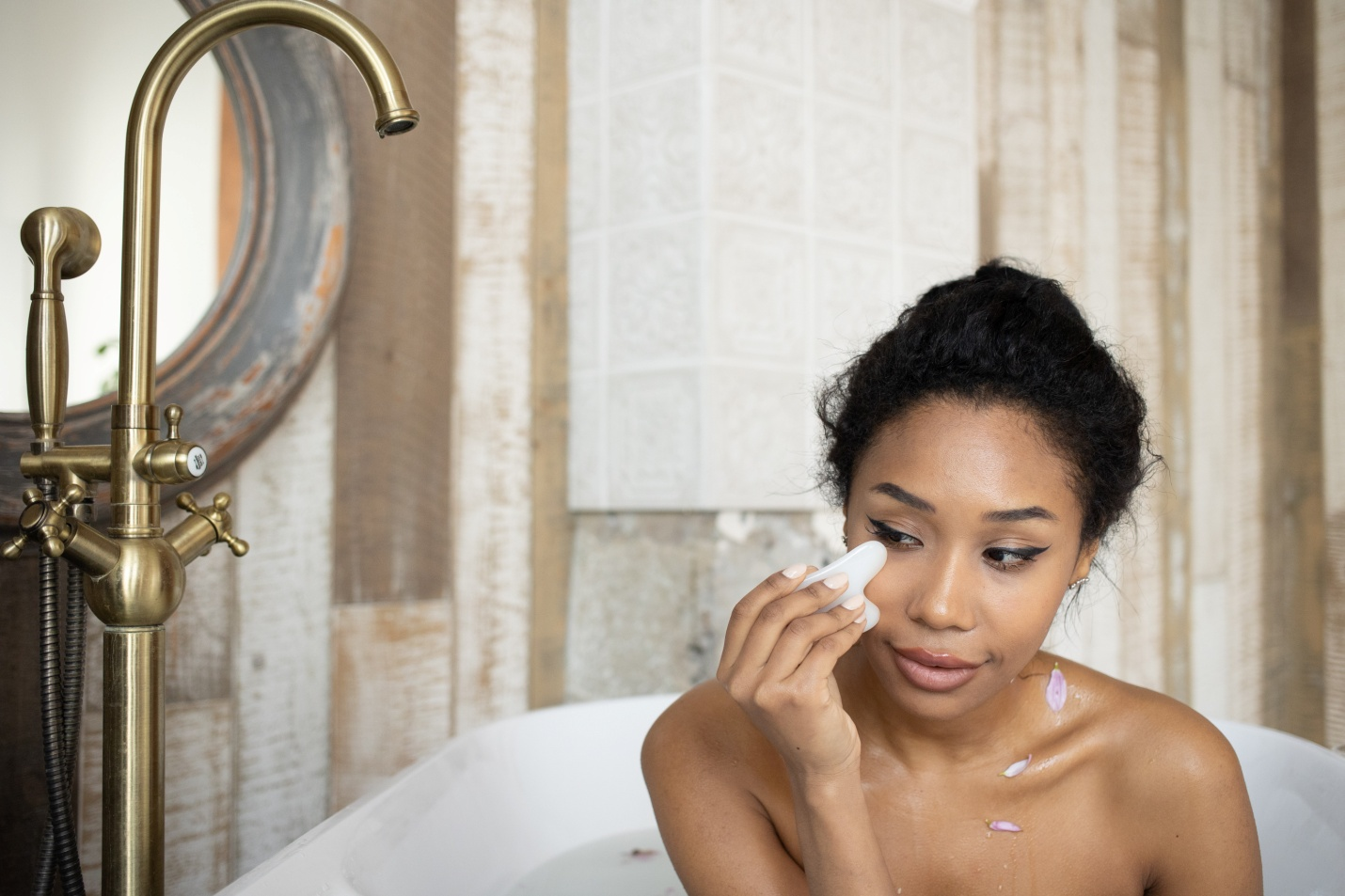  A woman uses gua sha while sitting in a tub