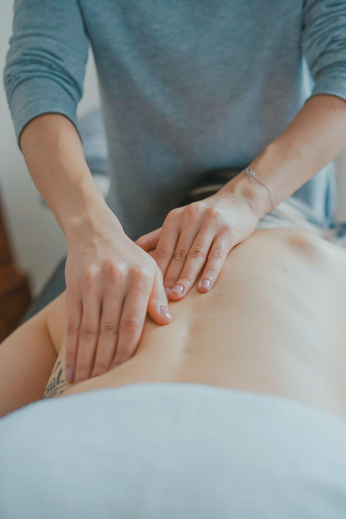 : Image of the hands and arms of a professional massaging the back of a client