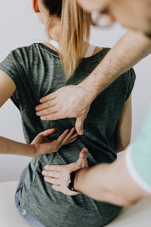 A chiropractor is checking a patient for pain areas