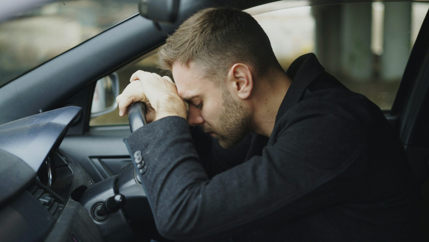 Driver experiencing a driving headache caused by neck tension during a long trip